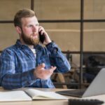 serious-bearded-man-talking-cellphone-workplace.jpg